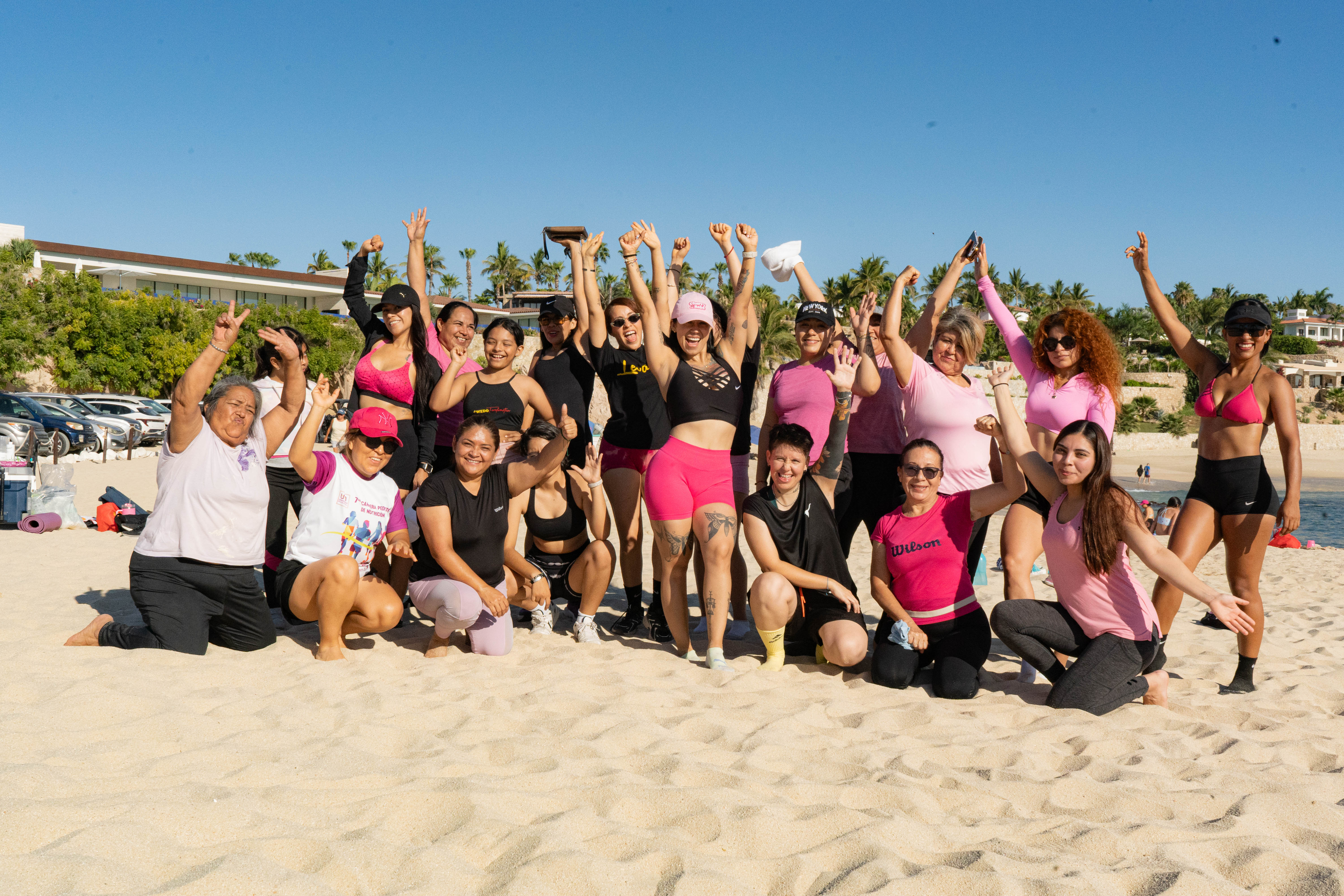 Grupo celebrando con brazos en alto en la playa