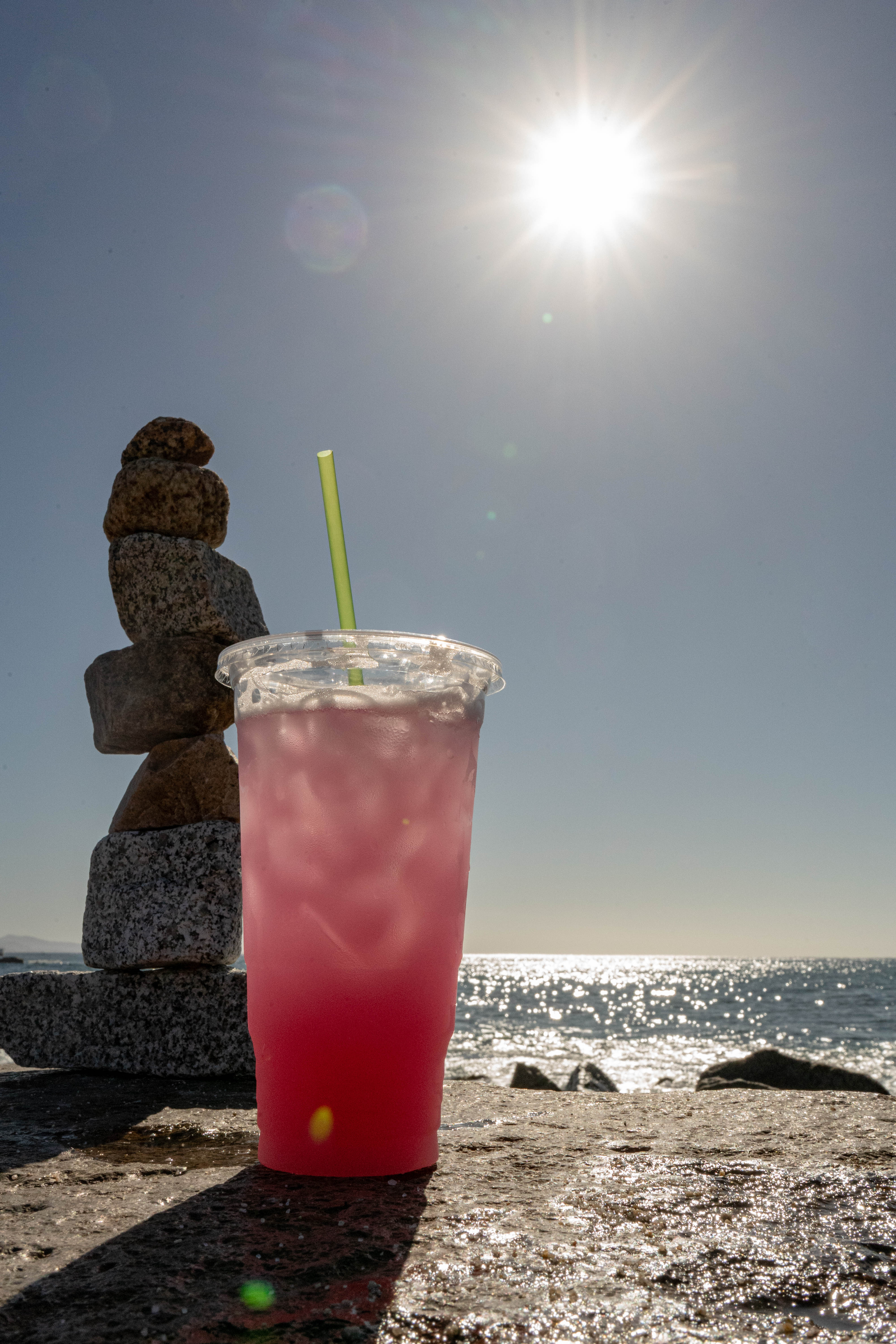 Bebida rosa con piedras apiladas bajo el sol