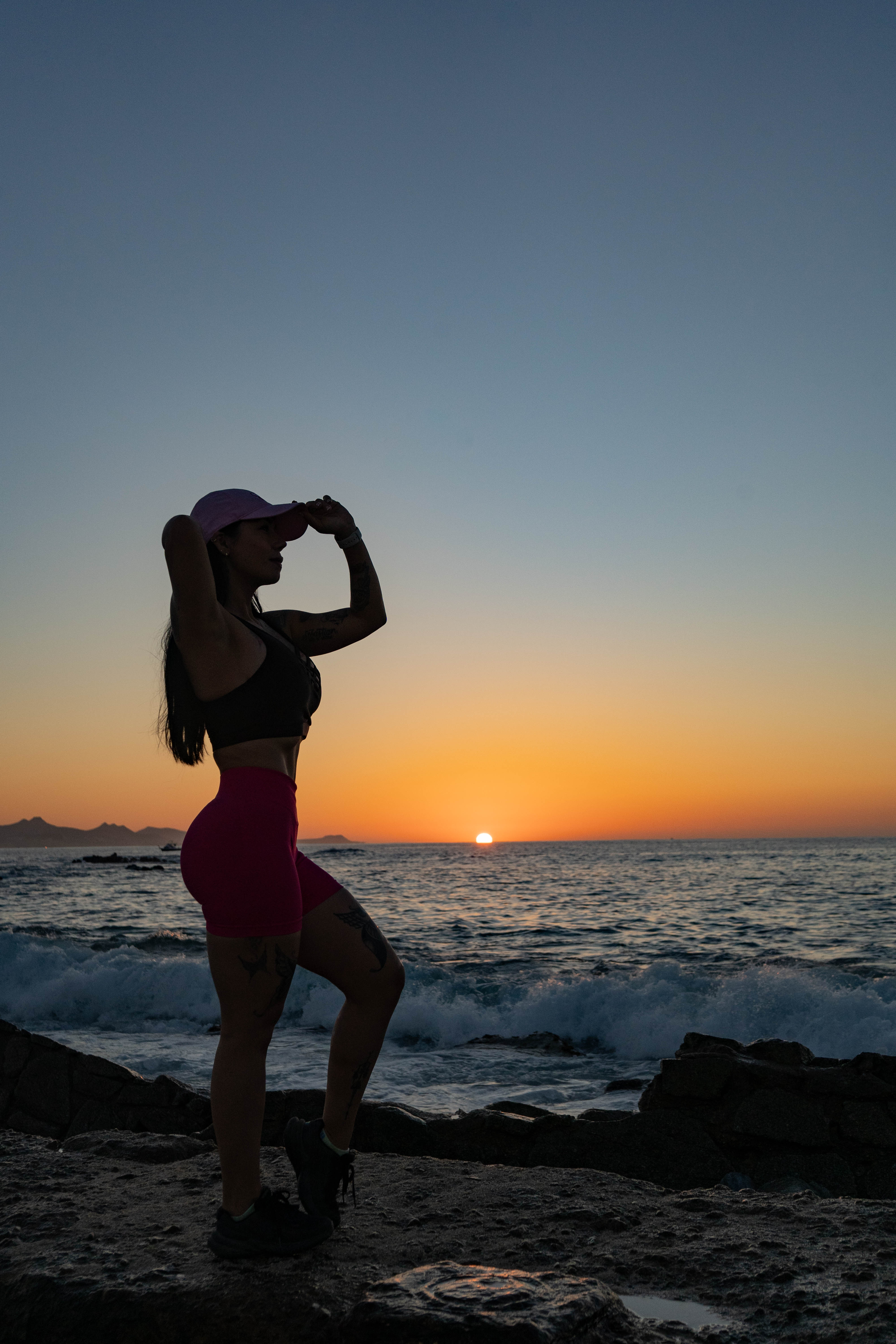 Silueta de Patricia ajustando su gorra al atardecer