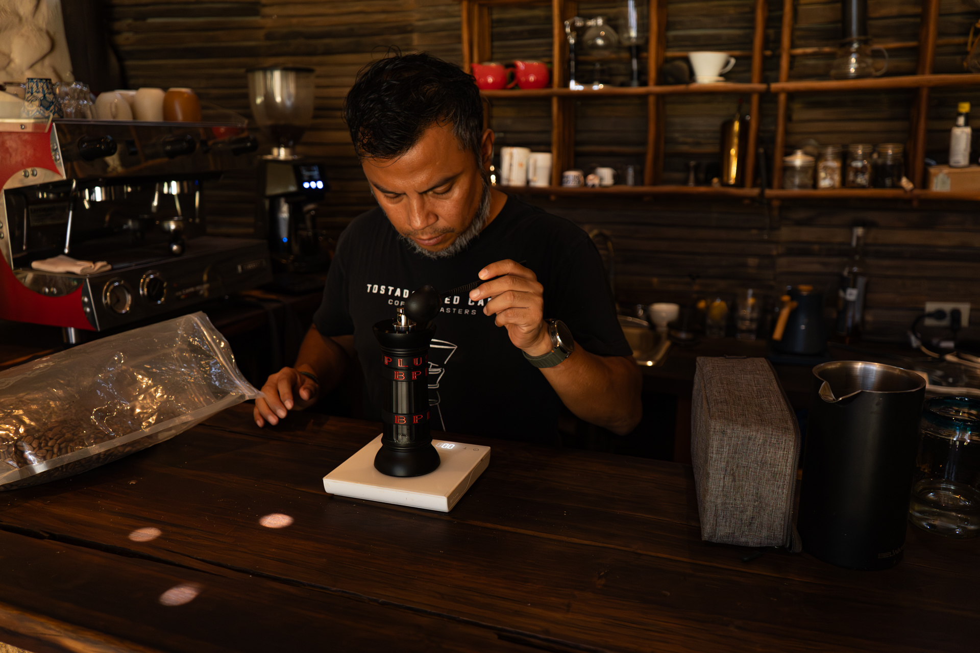 Barista ajustando el molino manual en la barra del café