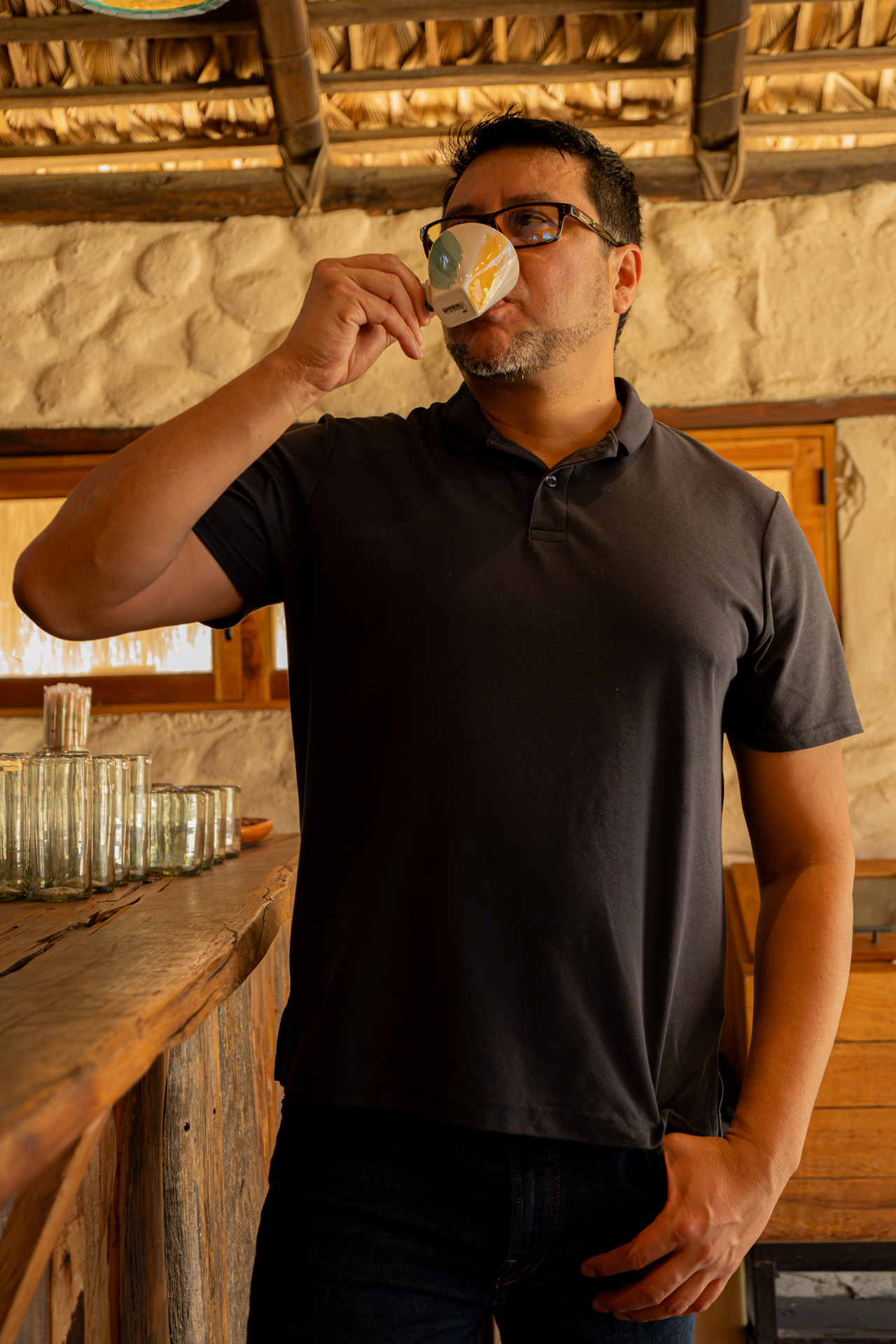 Hombre tomando café en el interior rústico de la palapa