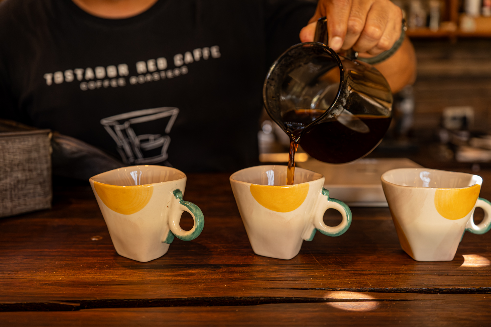 Vertiendo café en tres tazas de cerámica